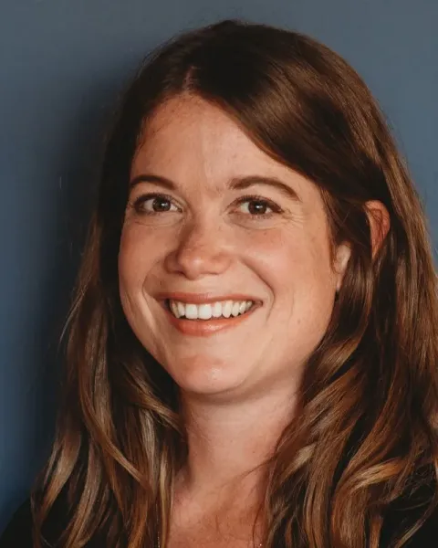 Portrait of Ellory Monks, smiling, with long auburn hair