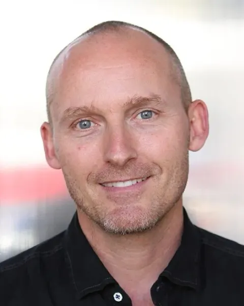 Portrait of Jon Belmonte, smiling, in a black shirt